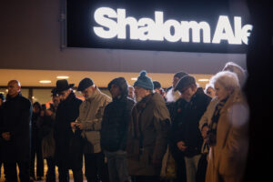 Menschen stehen auf dem Platz. Es ist dunkel.