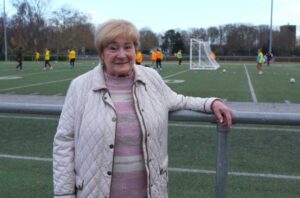 Frau steht am Rande eines Fußballplatzes