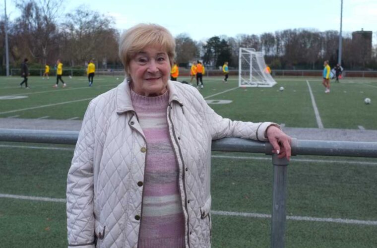 Frau steht am Rande eines Fußballplatzes