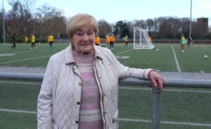 Frau steht am Rande eines Fußballplatzes