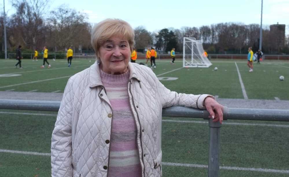 Frau steht am Rande eines Fußballplatzes