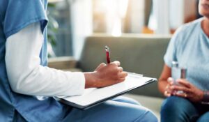 Pflegeperson macht sich Notizen während eines Gesprächs