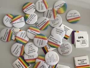 Regenbogenfarbene Anstecker mit demokratiestärkenden Sätzen drauf.