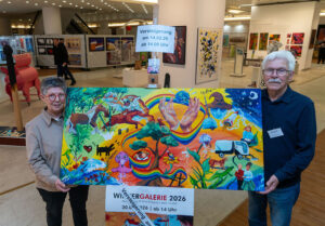 Eine Frau und ein Mann halten ein großes, queres und buntes Bild zwischen sich.