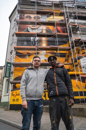 Lassana Dramé und Künstler Andrian Schnabel vor dem Wandbild. 