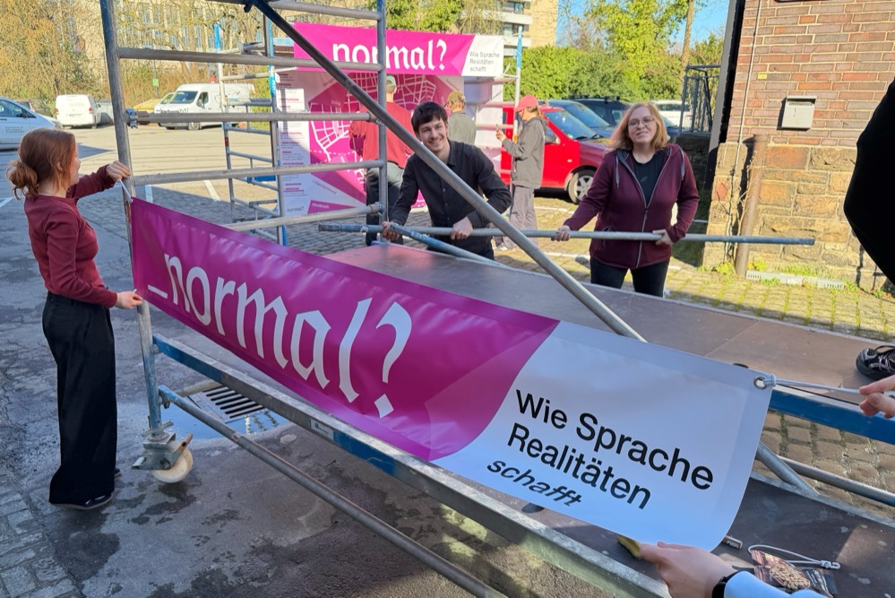 Studierende befestigen Transparente an Gerüsten