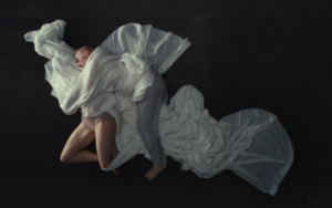 Darstellung von Tänzern, die ineinander verwickelt auf dem Boden liegen