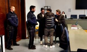 Gerichtssaal mit Angeklagten, zwei Anwälten und zwei Justizbeamten