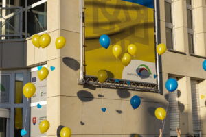 Gelbe und blaue Luftballons mit Wunschkarten steigen in den Himmel auf