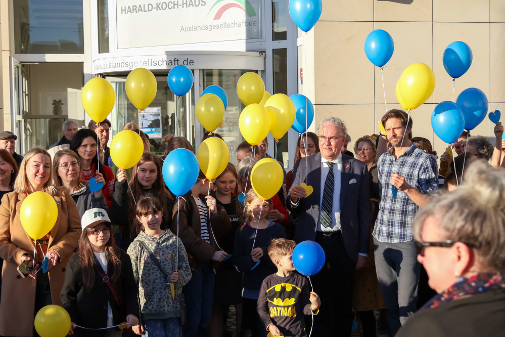 Blaue und gelbe Ballons mit Wunschkarten werden von Besucher:innen in den Himmel geschickt