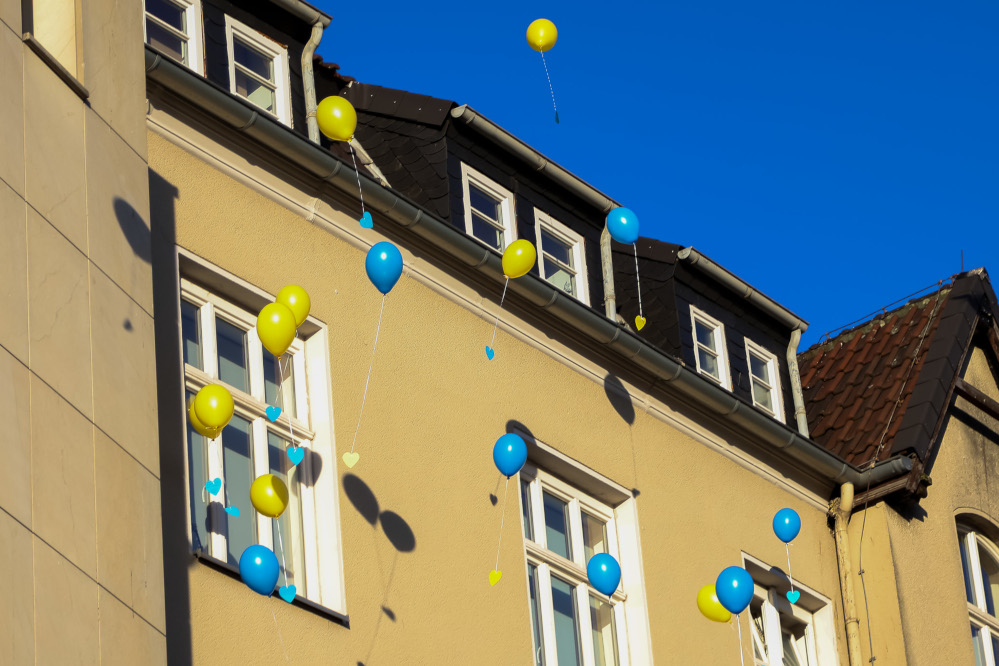 Gelbe und blaue Luftballons mit Wunschkarten steigen in den Himmel auf