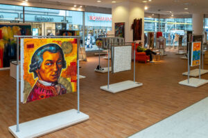 Ständer mit einzelnen Bildern stehen entlang der Gänge.