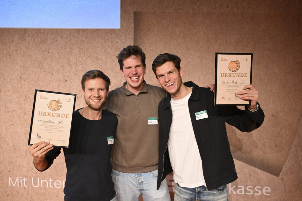 Drei Männer mit Urkunden in der Hand