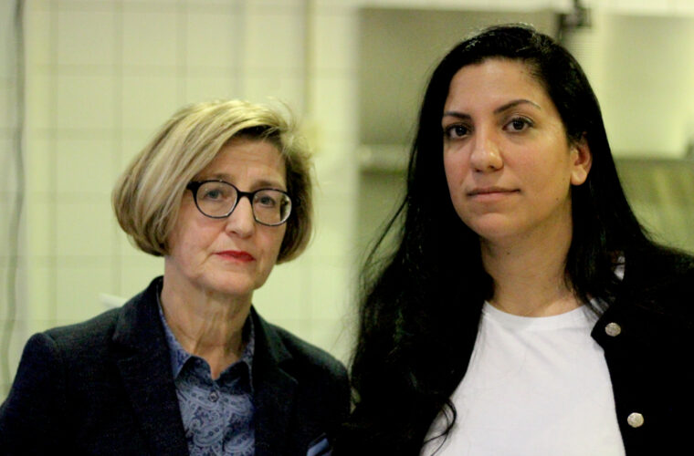Heike Bettermann und Selvi Aksünger stehen vor der Cafeteria und schauen in die Kamera