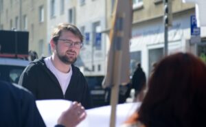 Lukas Wiens guckt auf das Banner und die Menschen direkt vor ihm. Er läuft dabei rückwärts hinter dem Demontagen