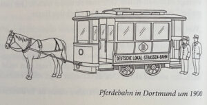 Zu Sehen ist eine Pferdebahn in Dortmund um 1900 - so die Bildunterschrift. Das Bild besteht aus schwarzen Konturen der Pferdebahn auf der steht: "DEUTSHCE LOKAL-STRASSEN-BAHN", darüber ein B in einer Raute. Neben der Bahn stehen zwei Uniformierte Personen.