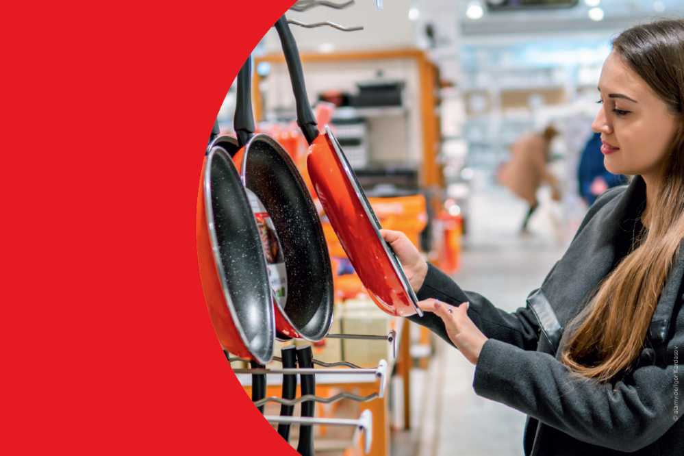 Frau betrachtet Pfannen in einem Laden