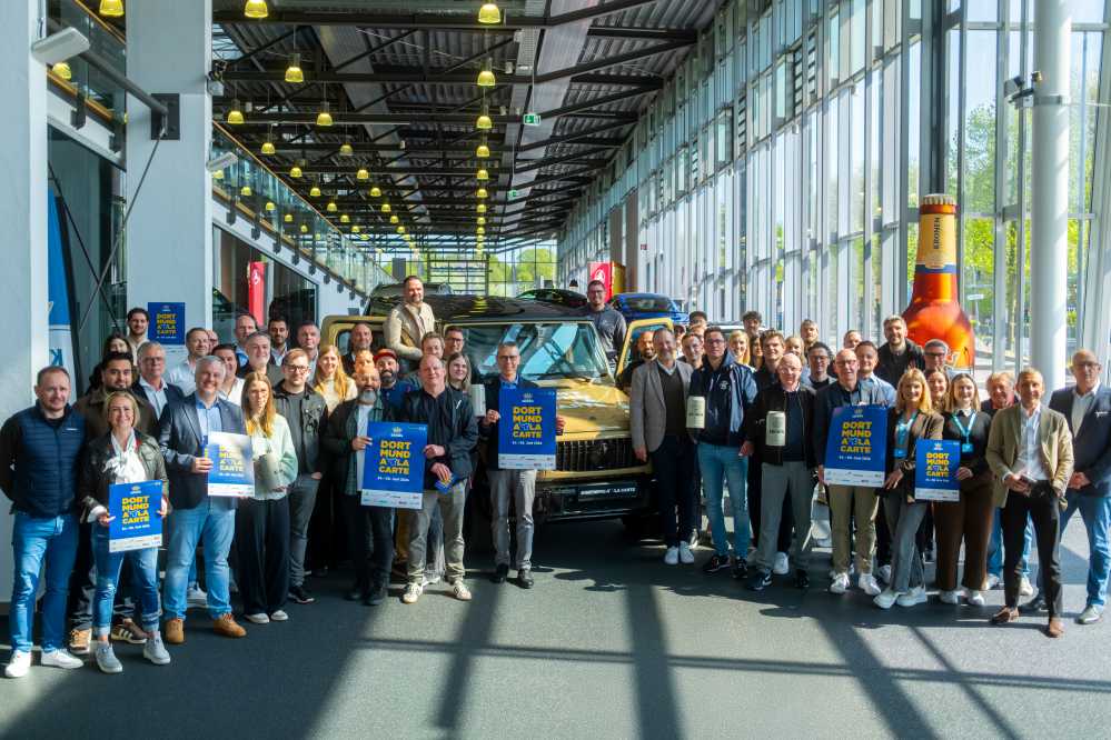 Veranstalter:innen präsentieren Programmheft im Autohaus