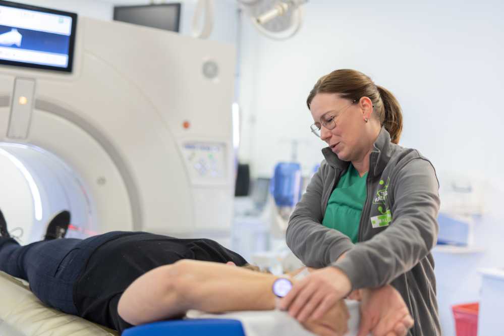 Mitarbeiterin der Radiologie mit einem Patientin vor einer Computertomographie