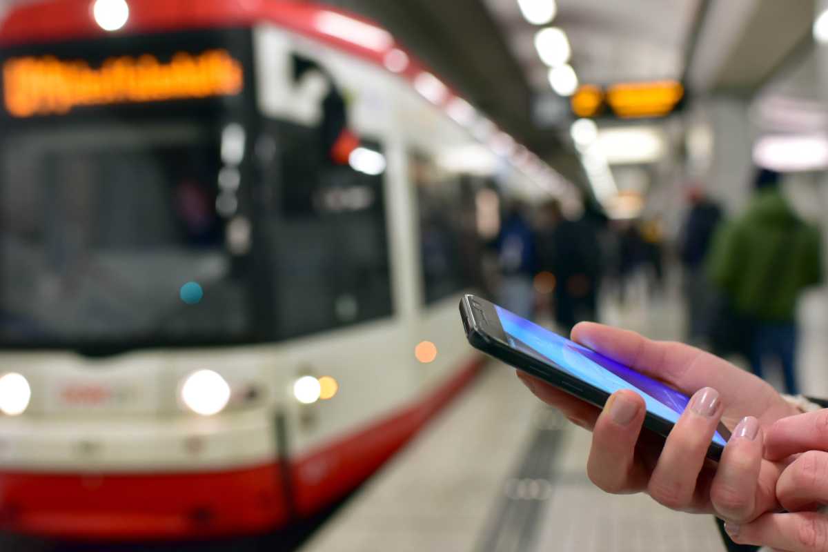 U Bahn fährt ein: Person nutzt Handy zum Ticket buchen