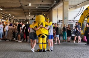 Maskottchen Emma von hinten mit zwei Fans. 