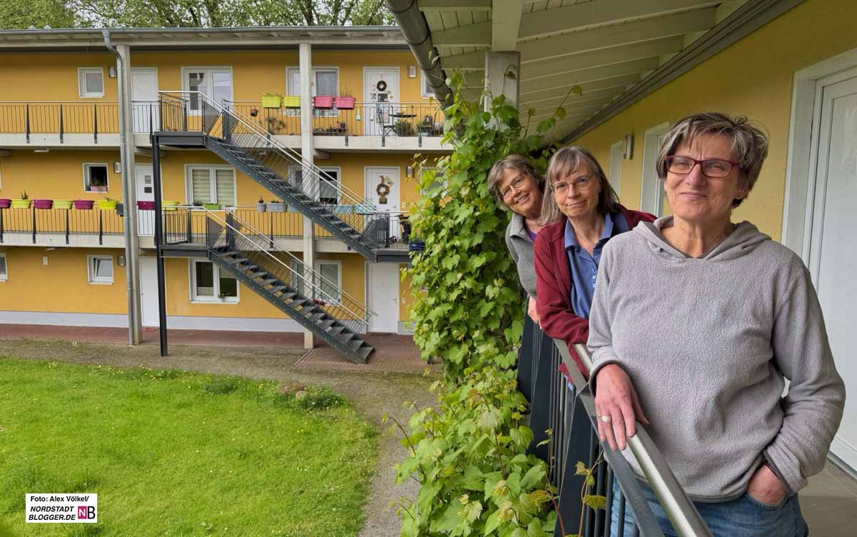 Drei Frauen stehen hintereinander am Geländer im Laubengang.