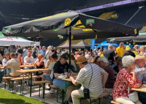 Besucher:innen sitzend auf den Bierbänken im Stadion. 
