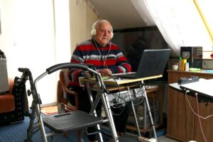 Alter Mann mit Rollator an seinem Schreibtisch