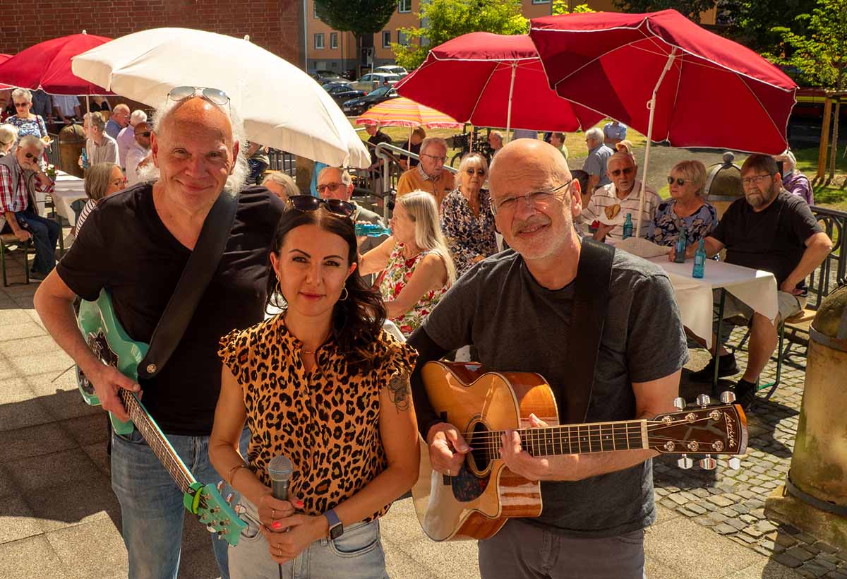 Das Bild zeigt das Trio vor Publikum