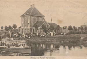 Das Bild zeigt Gebäude und ein Motorboot am Hardenberg-Hafen.