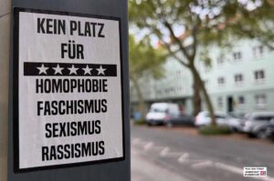 Das Bild zeigt einen Aufkleber an einem Straßenschild - Text: Kein Platz für Homophobie Faschismus Sexismus Rassismus