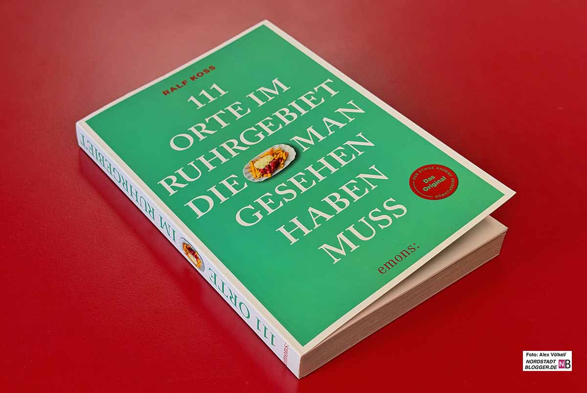 Das Bild zeigt das grüne Buch auf einem roten Tisch