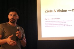 Mann gestikuliert vor einer Beamerleinwand