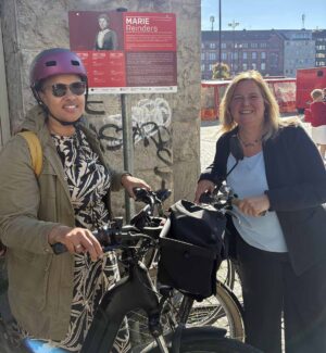 Zwei Frauen mit dem Fahrrad vor einer Gedenktafel
