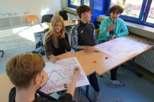 Schüler:innen arbeiten an einem Plakat.