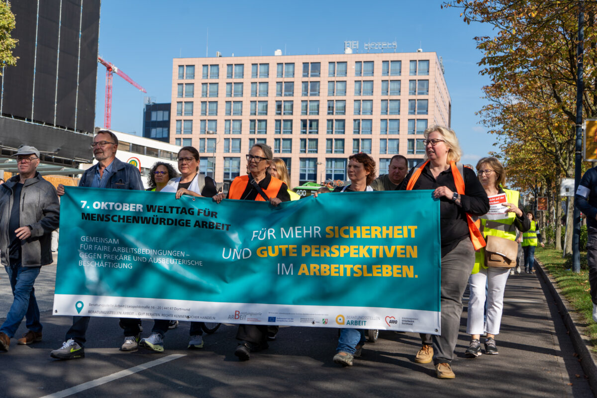 Männer und Frauen halten ein Banner und demonstrieren.