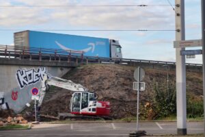 Kleiner Bagger vor einer Autobahnbrücke