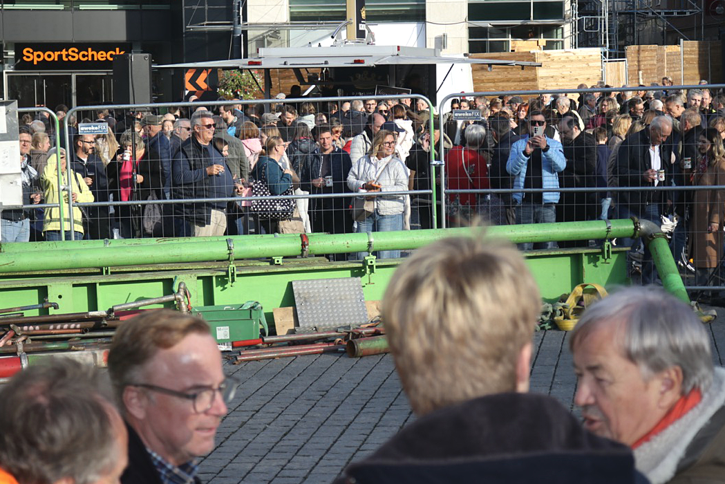 Menschenmenge hinter einem Bauzaun